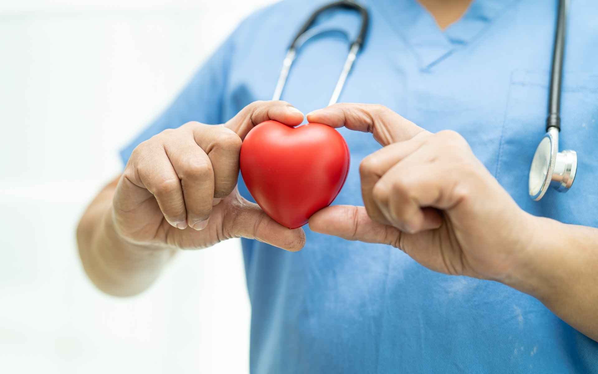 Ärztin trägt kleines rotes Herz zwischen den Händen
